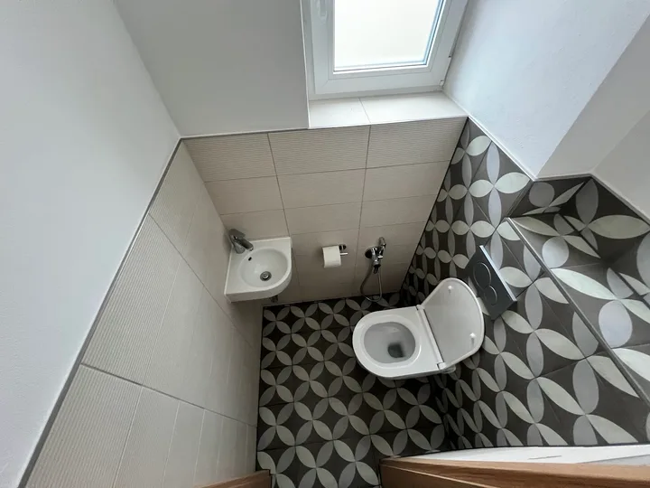 Koupelna se vzorovanou dlažbou a závěsným WC